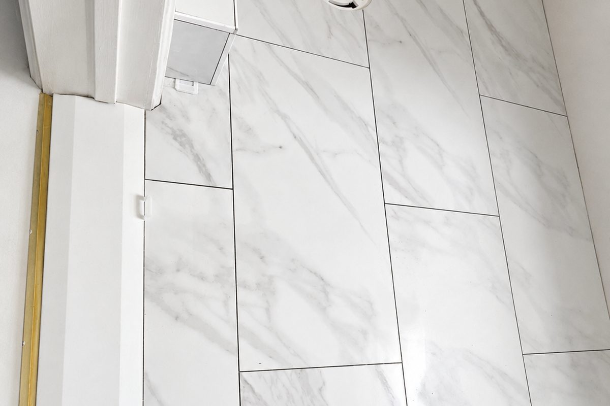 Before: marble-look floor tile set with spacers around the toilet flange during a Throgs Neck Bronx bathroom gut renovation