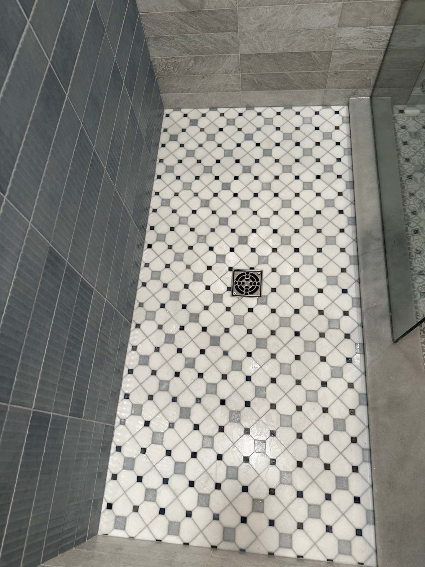 Marble mosaic shower floor with square drain and blue accent tile walls, NYC bathroom renovation