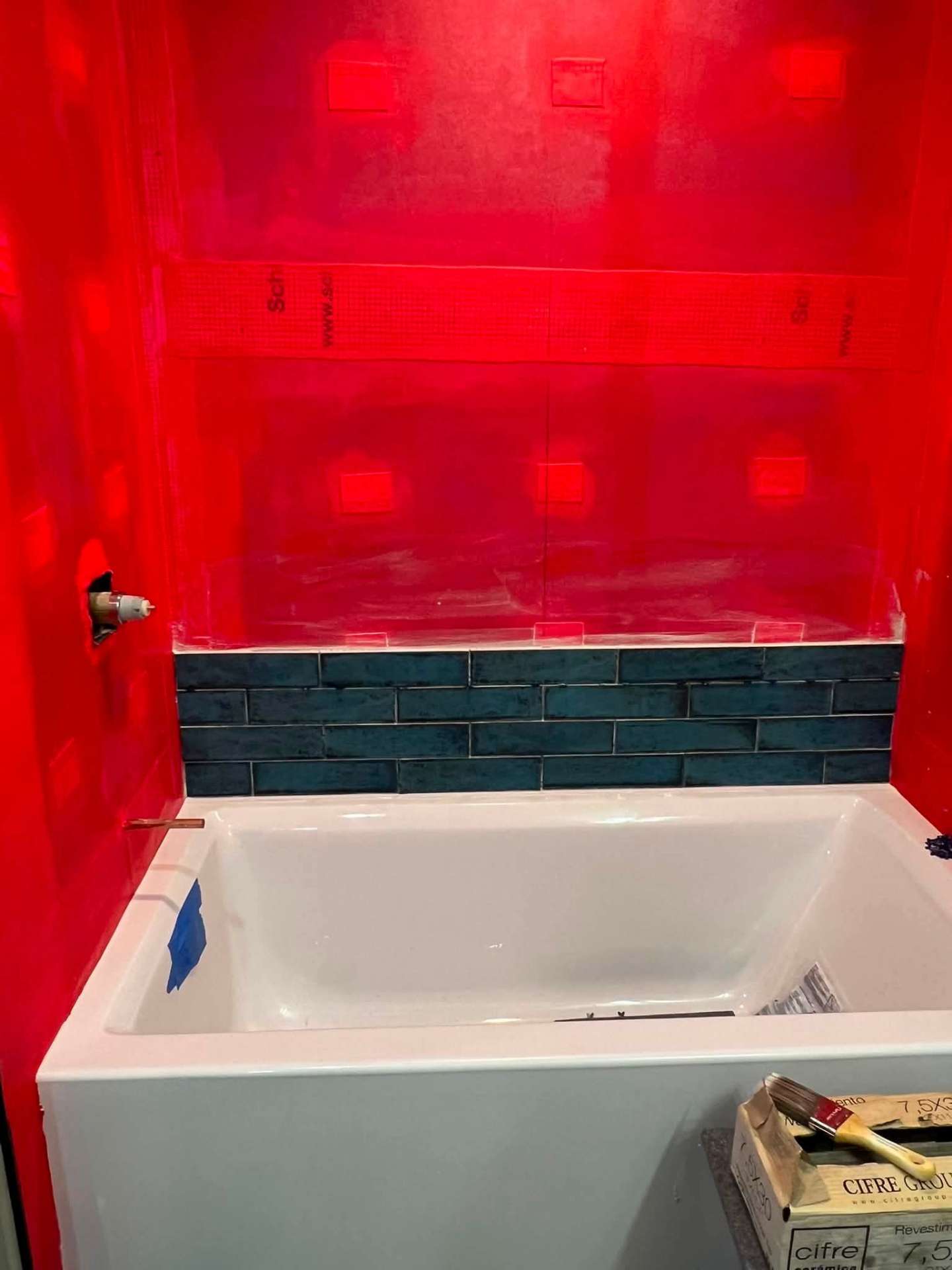 Bathroom renovation in progress with waterproofing membrane and blue tile surround around new tub
