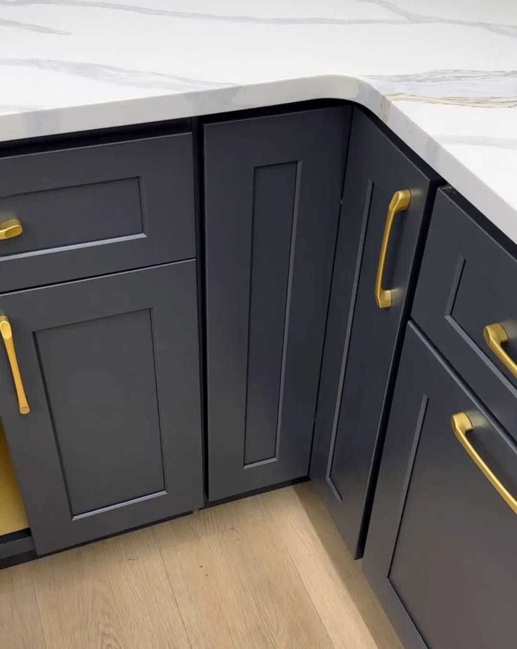 Navy kitchen cabinets with brass handles and white quartz countertop